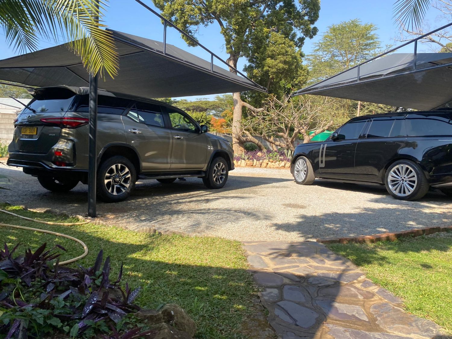Two shade-net carports over parked SUVs